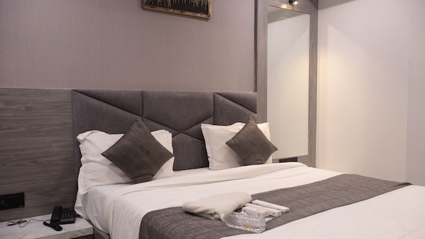 Une chambre d’hôtel moderne avec un grand lit, une table de chevet avec un téléphone et un miroir au mur.