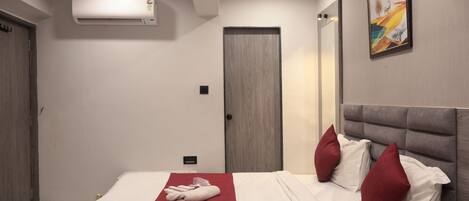 Quarto de hotel com uma cama, um cobertor vermelho e um quadro na parede.