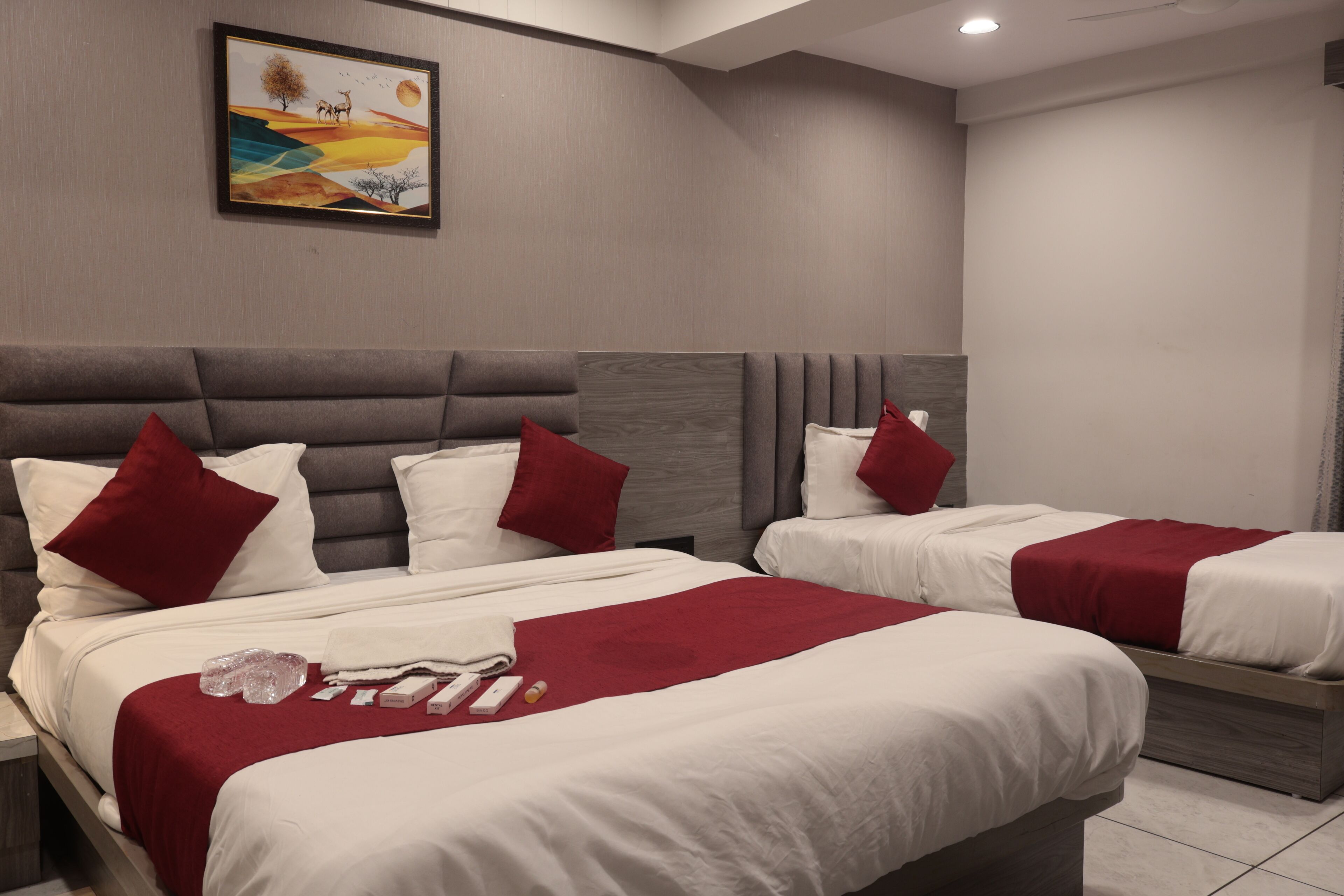 Une chambre d’hôtel avec deux lits, chacun agrémenté de draps blancs et de touches de couleur rouge, d’une tête de lit grise et d’une œuvre d’art encadrée au mur.