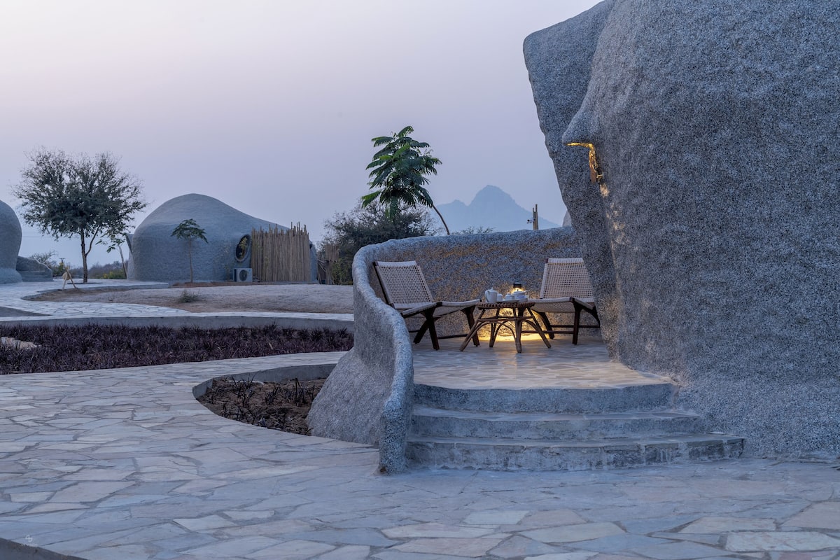 A stone bench with a table and chairs in a landscaped area with steps leading up to it.