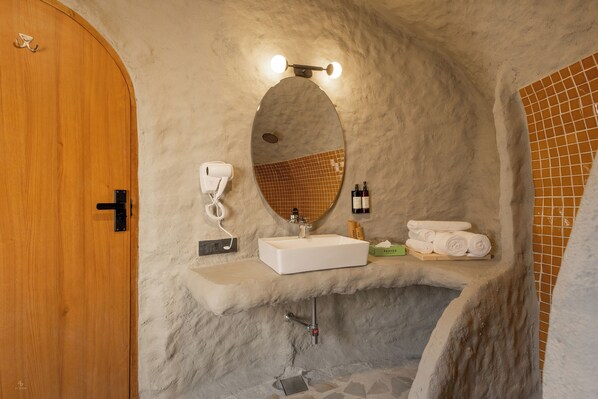 A bathroom with a wooden door, a white sink, a mirror, and a towel rack.