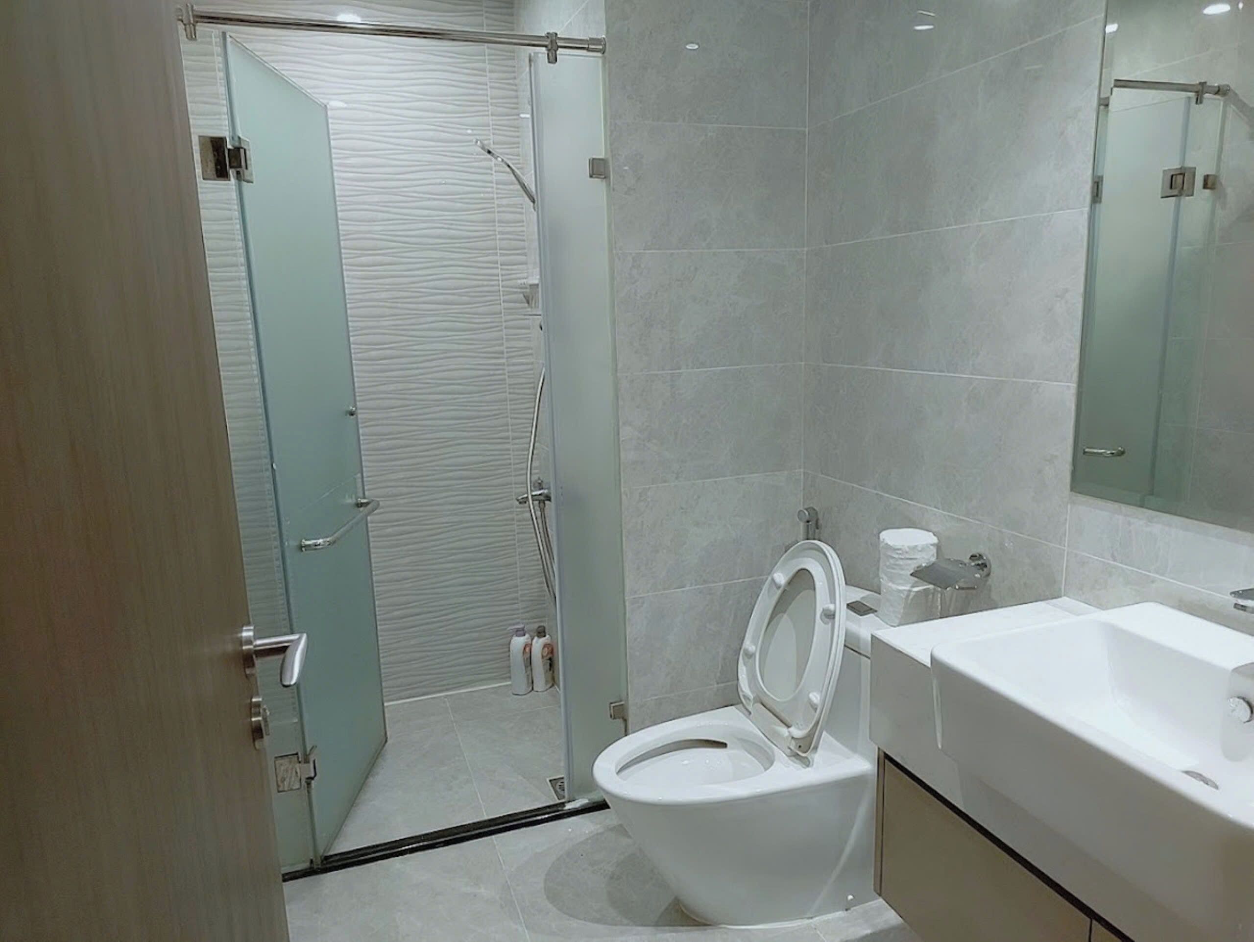 A modern bathroom with a toilet, sink, and shower.
