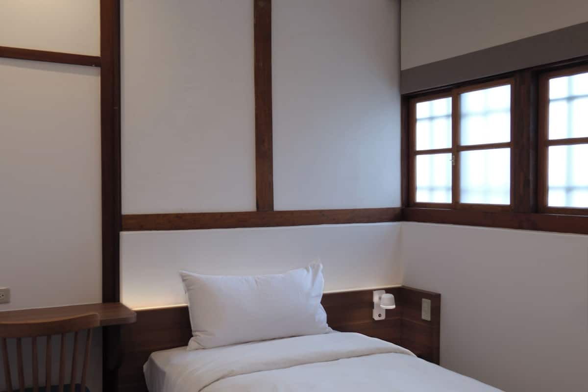 A hotel room with a bed, a desk, and a chair.