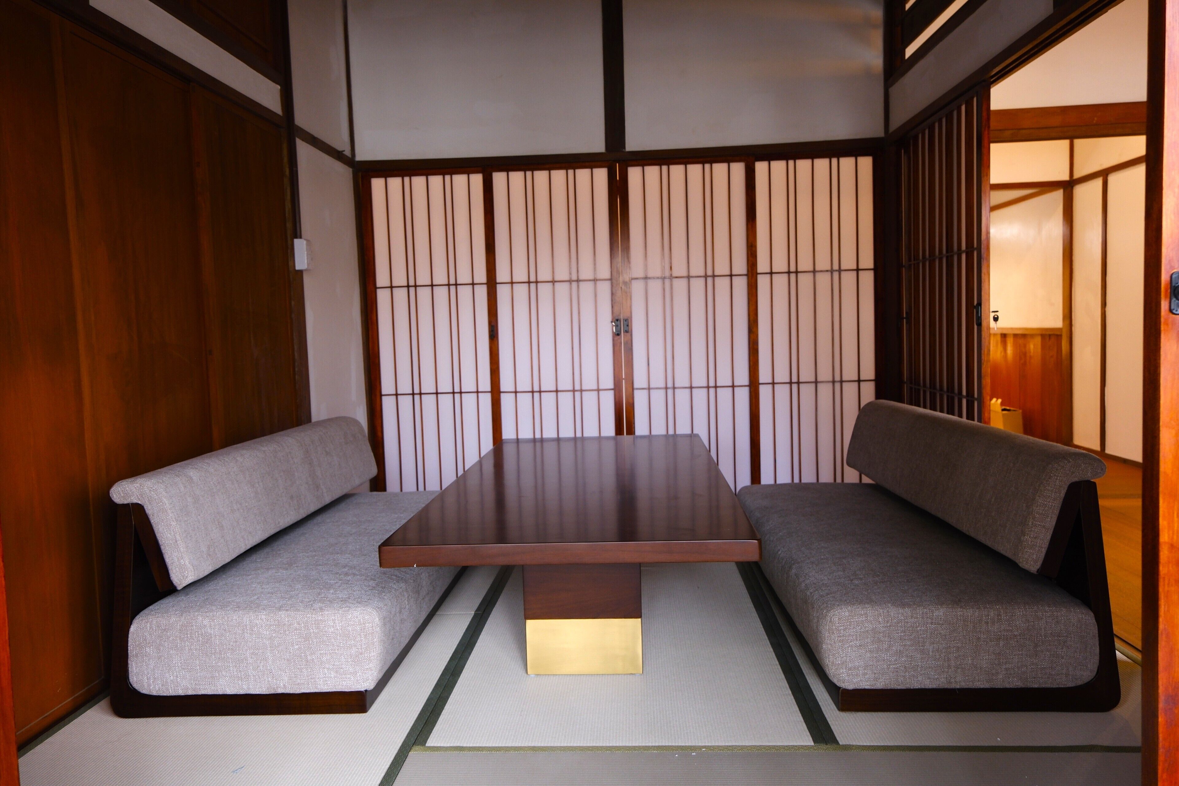 A traditional Japanese room with tatami flooring, a low wooden table, and two tatami mats with cushions.