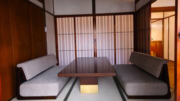 A traditional Japanese room with tatami flooring, a low wooden table, and two tatami mats with cushions.