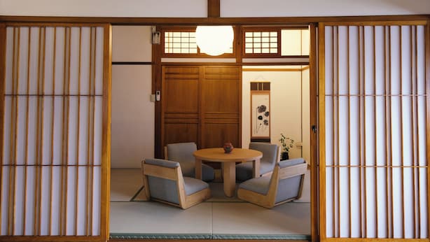 Una habitación japonesa tradicional con suelo de tatami, una mesa de madera baja y dos sillas.