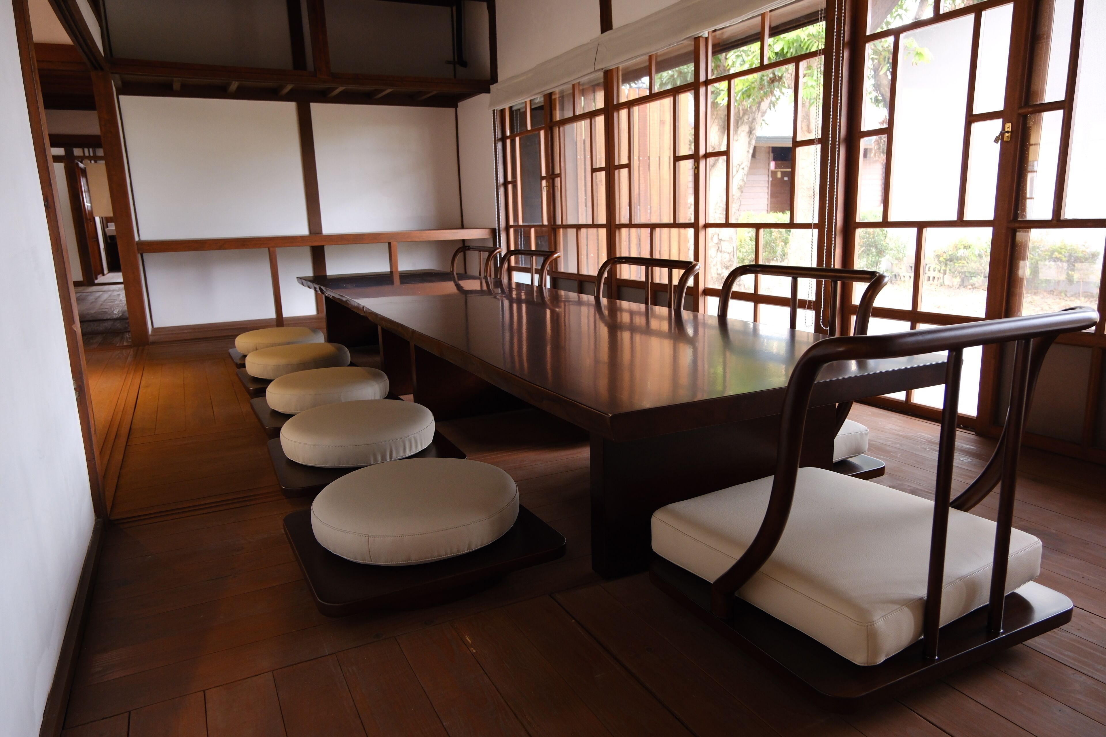 A traditional Japanese-style room with tatami flooring, a low wooden table, and tatami mats with cushions.