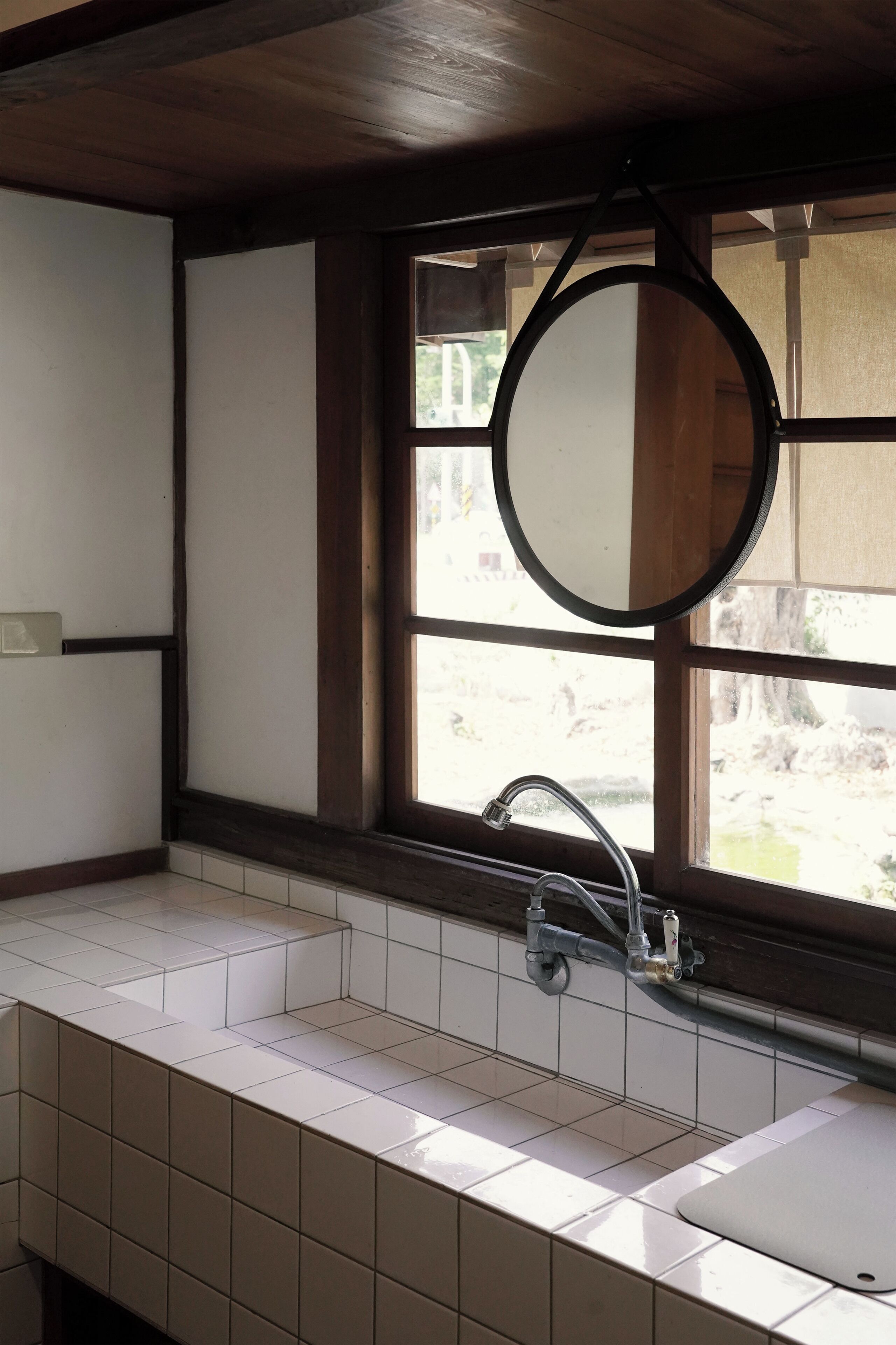 A bathroom with a window, a sink, and a mirror.