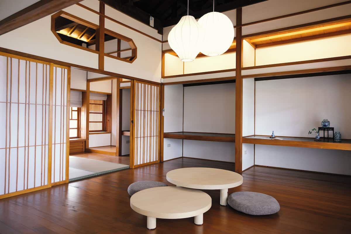 A traditional Japanese room with tatami flooring, shoji screens, and a low wooden table with cushions.