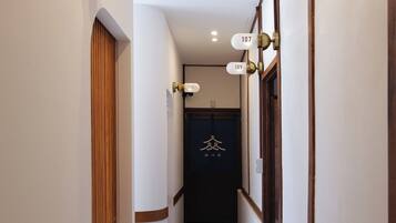 A narrow hallway with wooden flooring and white walls, featuring door numbers 107, 109, and 110.