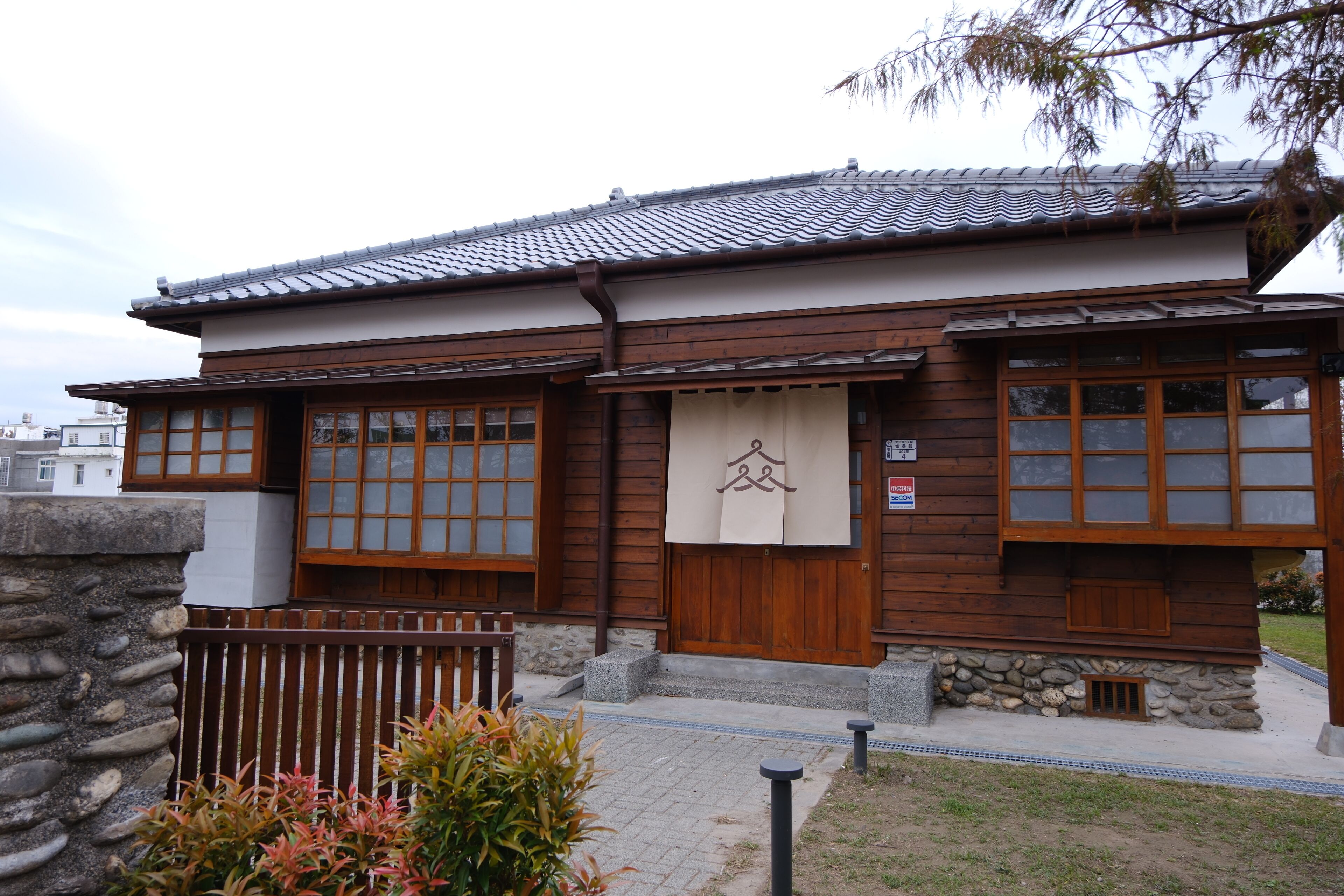 A traditional wooden building with a stone wall, wooden door, and windows.