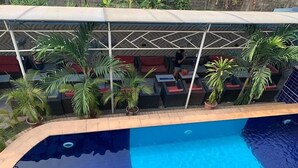 Zwembad met betegelde rand, omgeven door potplanten en buitenmeubels.