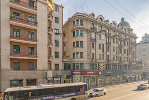 A multi-story building with balconies, a bus, and cars on the street.