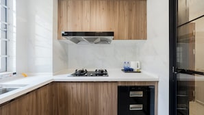 A modern kitchen with wooden cabinets, a black range hood, and a dishwasher. - Gangxiahui Hotel Apartments (Shenzhen)