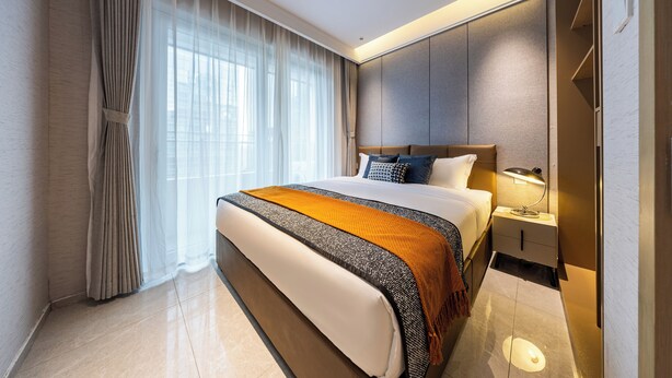A modern hotel room with a large bed, a bedside table with a lamp, and a wardrobe. - Gangxiahui Hotel Apartments (Shenzhen)