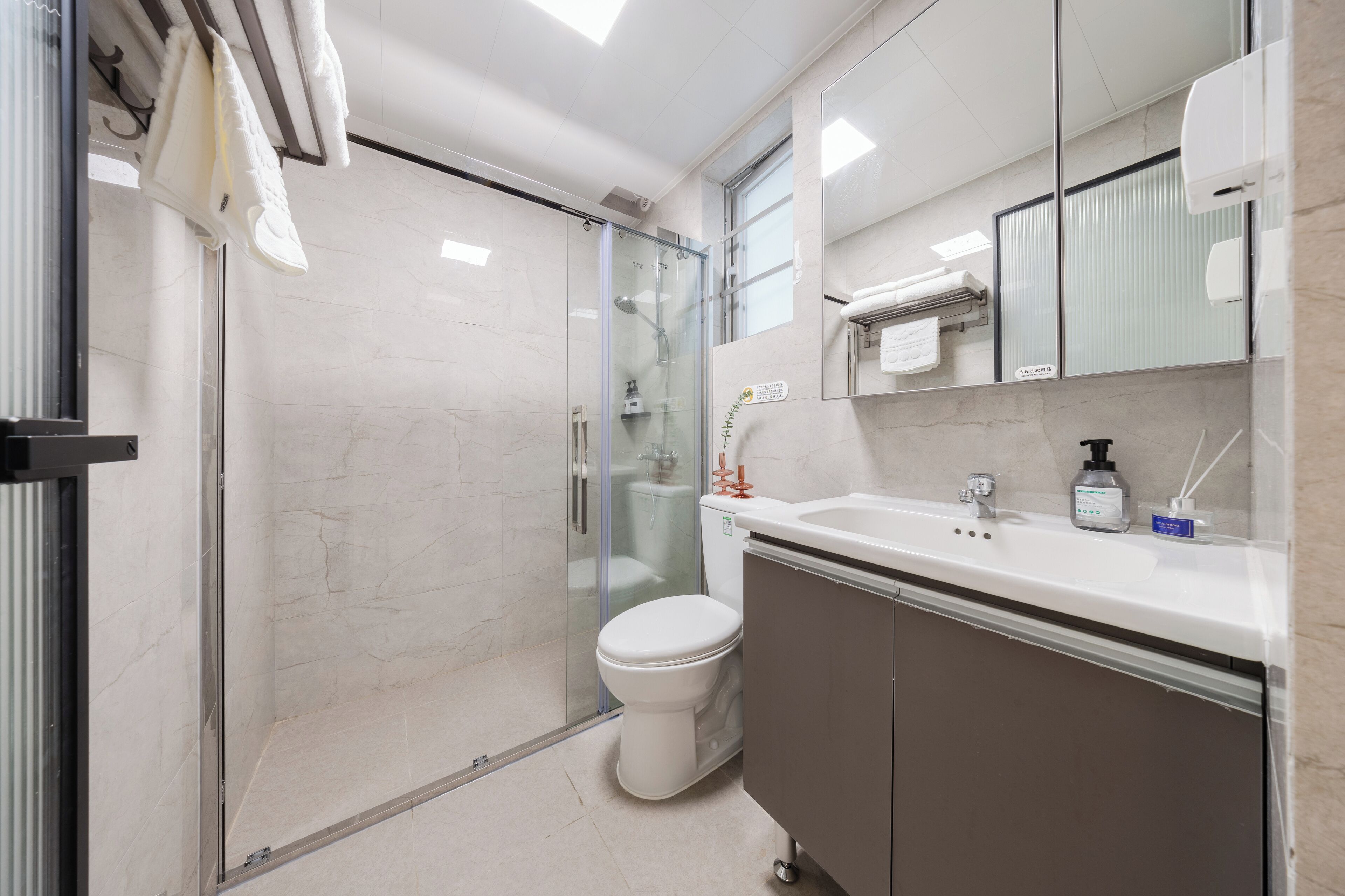 A modern bathroom with a glass-enclosed shower, a white toilet, and a vanity with a mirror and sink.