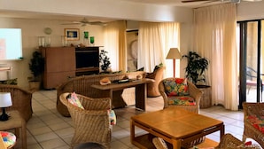Un salon avec des meubles en osier, une table basse en bois et un ventilateur de plafond.