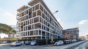 A modern multi-story building with balconies, a parking lot, and a street view. - GuestHost - Ostiense Modern & Stylish Apt with Terrace (Roma)