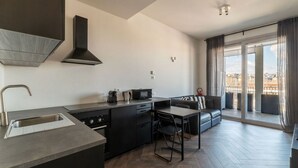 A modern kitchen with a built-in island, a dining area with a sofa, and a large sliding glass door to the outside. - GuestHost - Ostiense Modern & Stylish Apt with Terrace (Roma)