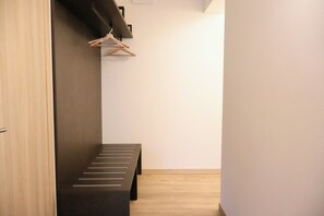 A hallway with a bench, wooden floor, and a coat rack. - Family Bike Residence (Marone)