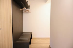 Un pasillo con un banco, suelo de madera y un perchero.