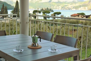 Un balcón con una mesa dispuesta para dos personas, una cafetera y dos vasos.