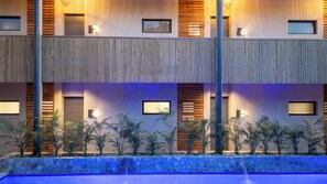 Un hôtel moderne doté d’une piscine, de plusieurs étages et d’un mur en pierre agrémenté de plantes.