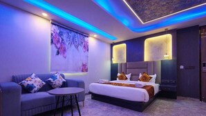 A modern hotel room with a large bed, a sofa, and a small table.