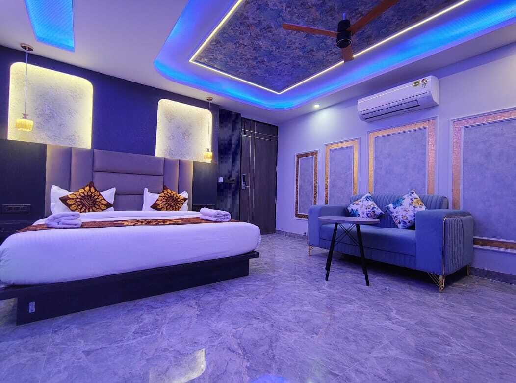 A modern bedroom with a large bed, a sofa, and a ceiling fan.