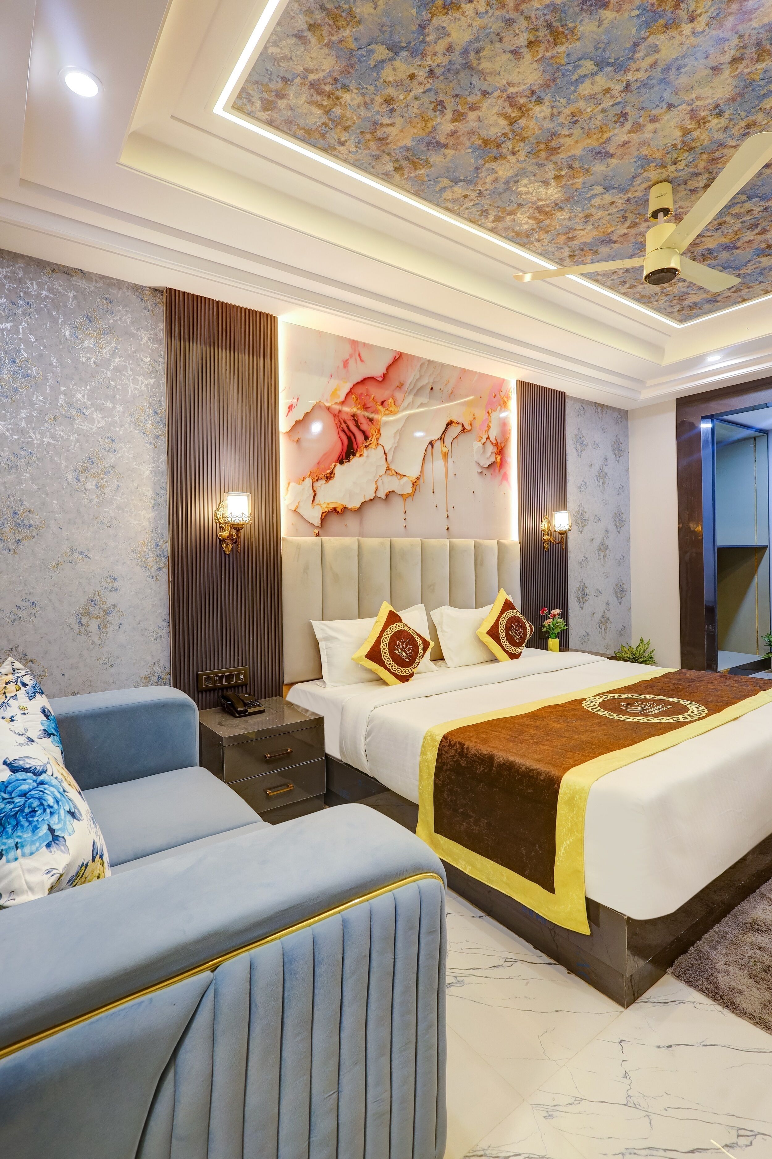 A modern hotel room with a large bed, a seating area, and a ceiling with a floral design.