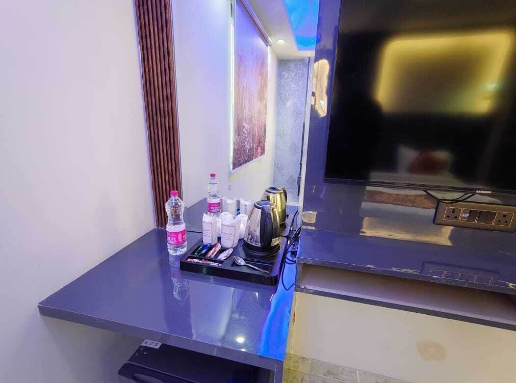 Habitación de hotel con televisor de pantalla plana, minibar y una mesa con artículos de aseo.