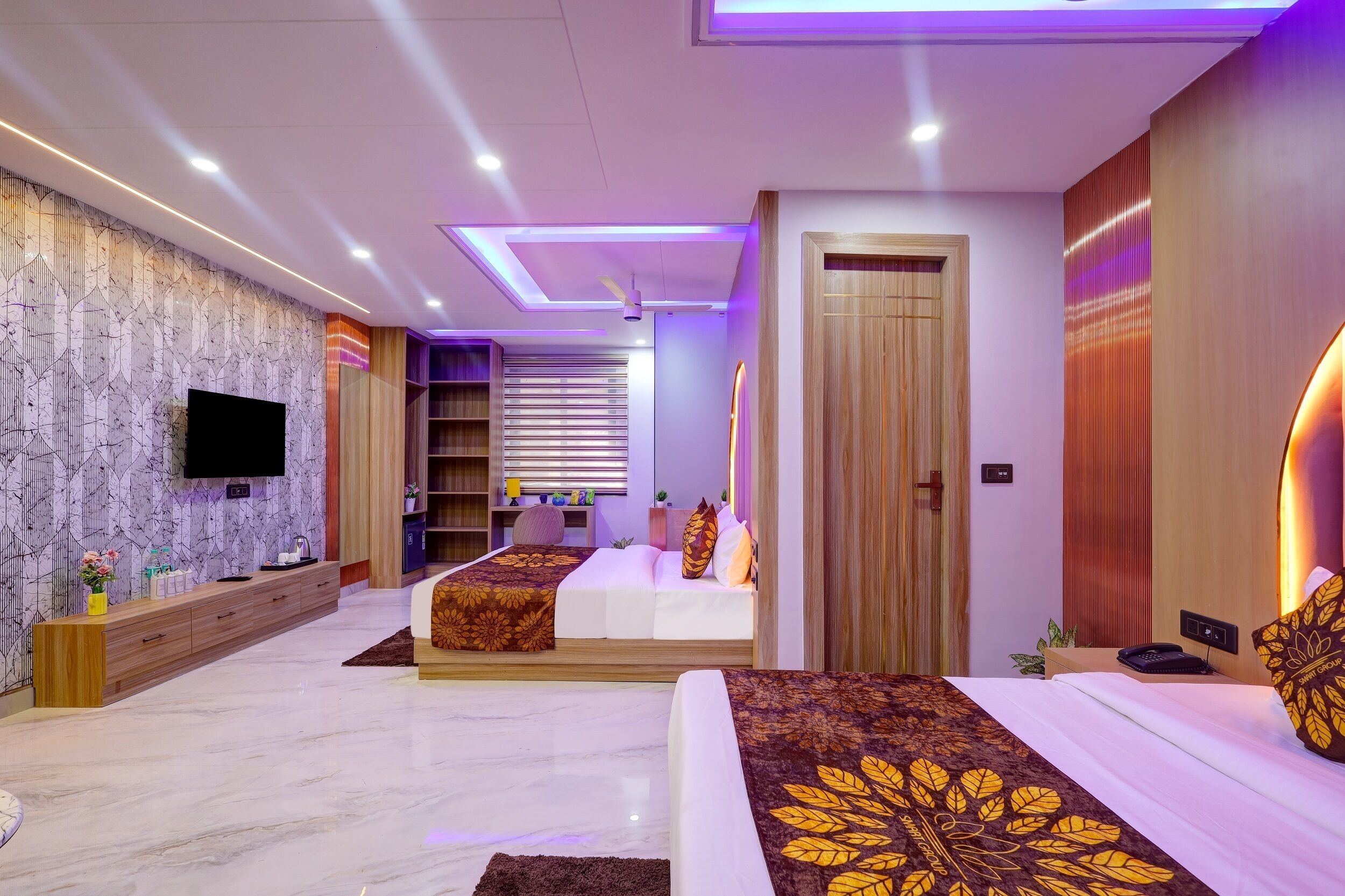 A modern hotel room with a large bed, a TV, a wooden wardrobe, and a bathroom with a shower and toilet.