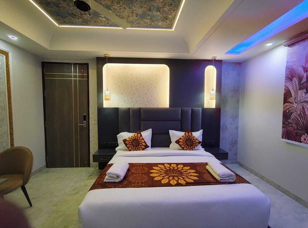 Una habitación de hotel moderna con una cama grande, cabecera oscura e iluminación empotrada en el techo.