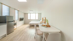 A compact hotel room with a kitchenette, a bed, a small dining table, and a TV. - Gyeongju Gampo Laviangrose Pool Villa (Gyeongju)