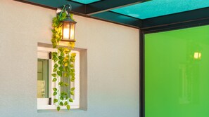A window with a hanging green plant and a wall-mounted lantern. - Gyeongju Gampo Laviangrose Pool Villa (Gyeongju)