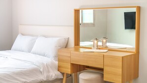 A hotel room with a wooden bedside table, a mirror, and a bed with white linens. - Gyeongju Gampo Laviangrose Pool Villa (Gyeongju)