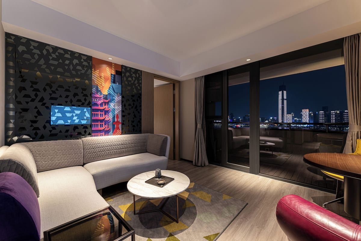 A modern living room with a sofa, a coffee table, and a view of a cityscape at night.