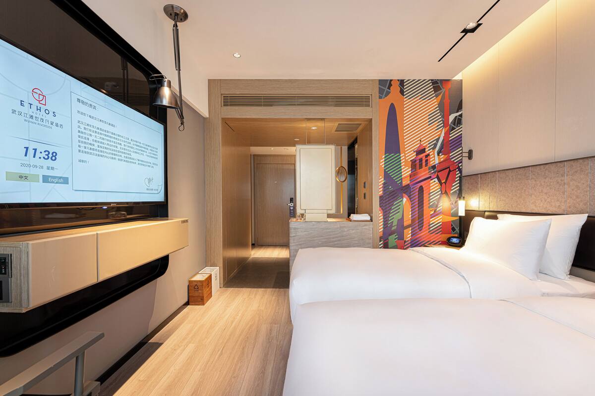 A hotel room with a bed, a TV, a desk, and a bathroom.