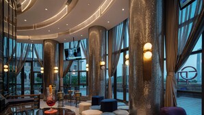 A modern lounge area with a bar, seating, and large windows offering views. - Ethos Hotel Wuhan Riverside (Wuhan)
