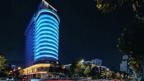 A modern hotel with a curved facade and illuminated blue lighting. - Ethos Hotel Wuhan Riverside (Wuhan)