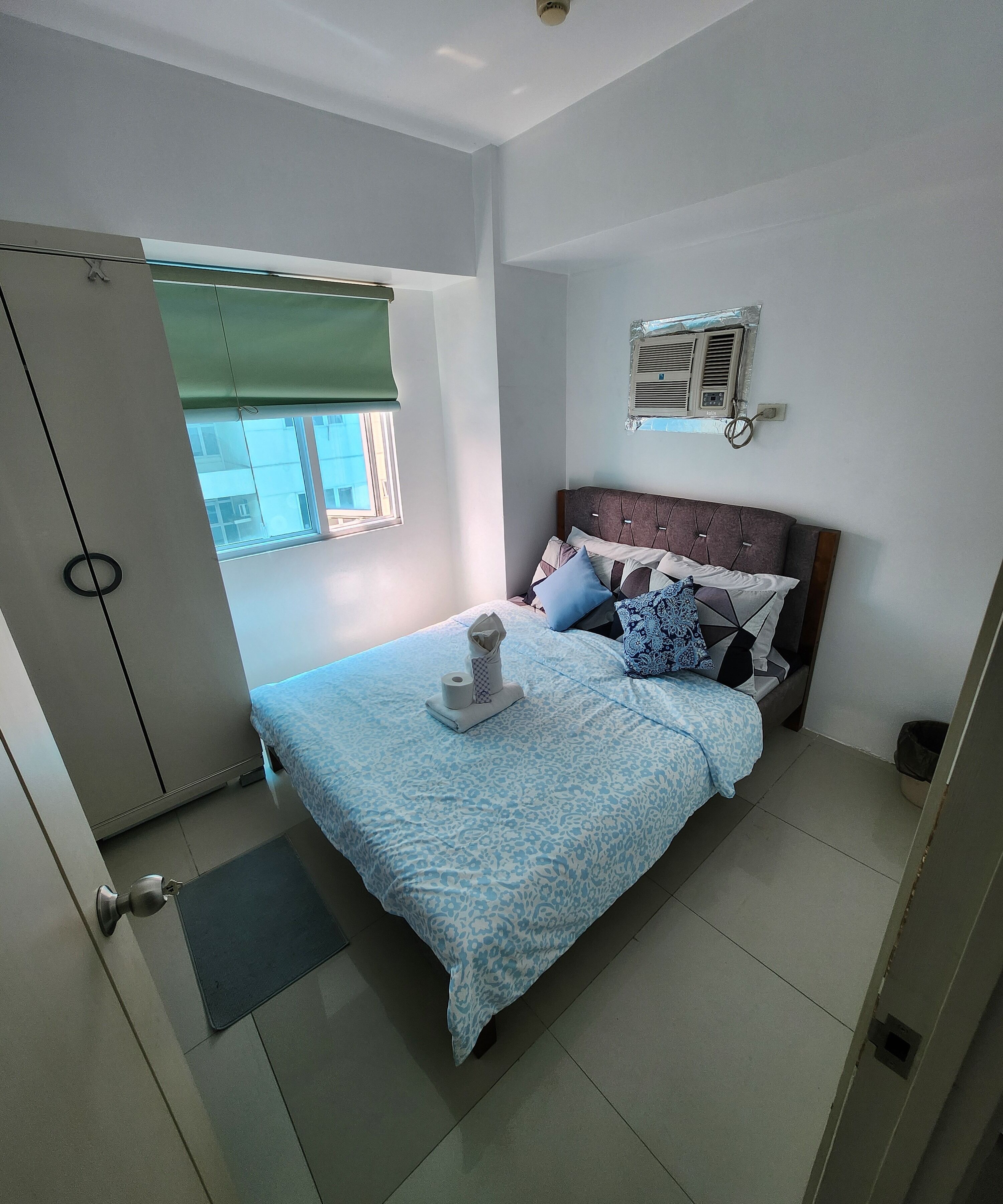 Een slaapkamer met een bed, een raam, een airconditioning en een deur.