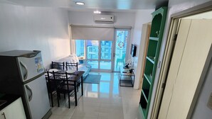 A modern kitchen with a refrigerator, dining table, and chairs. There is a sliding glass door leading to a balcony with a view of buildings. - Spacious 2BR at Sea Residences Near MOA - Family Stay (Pasay)