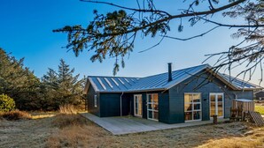 A modern house with a sloped roof, large windows, and a wooden deck. - "Kaapo" - 300m from the sea by Interhome (Løkken)