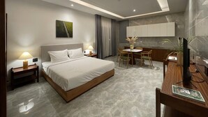 A modern hotel room with a large bed, bedside tables, a desk with a chair, a small round table, and a TV. - Field Villa Hoang Dieu (Ho Chi Minh City)