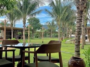 Relax in a serene garden setting with a distant mountain view, surrounded by lush greenery and comfortable seating.