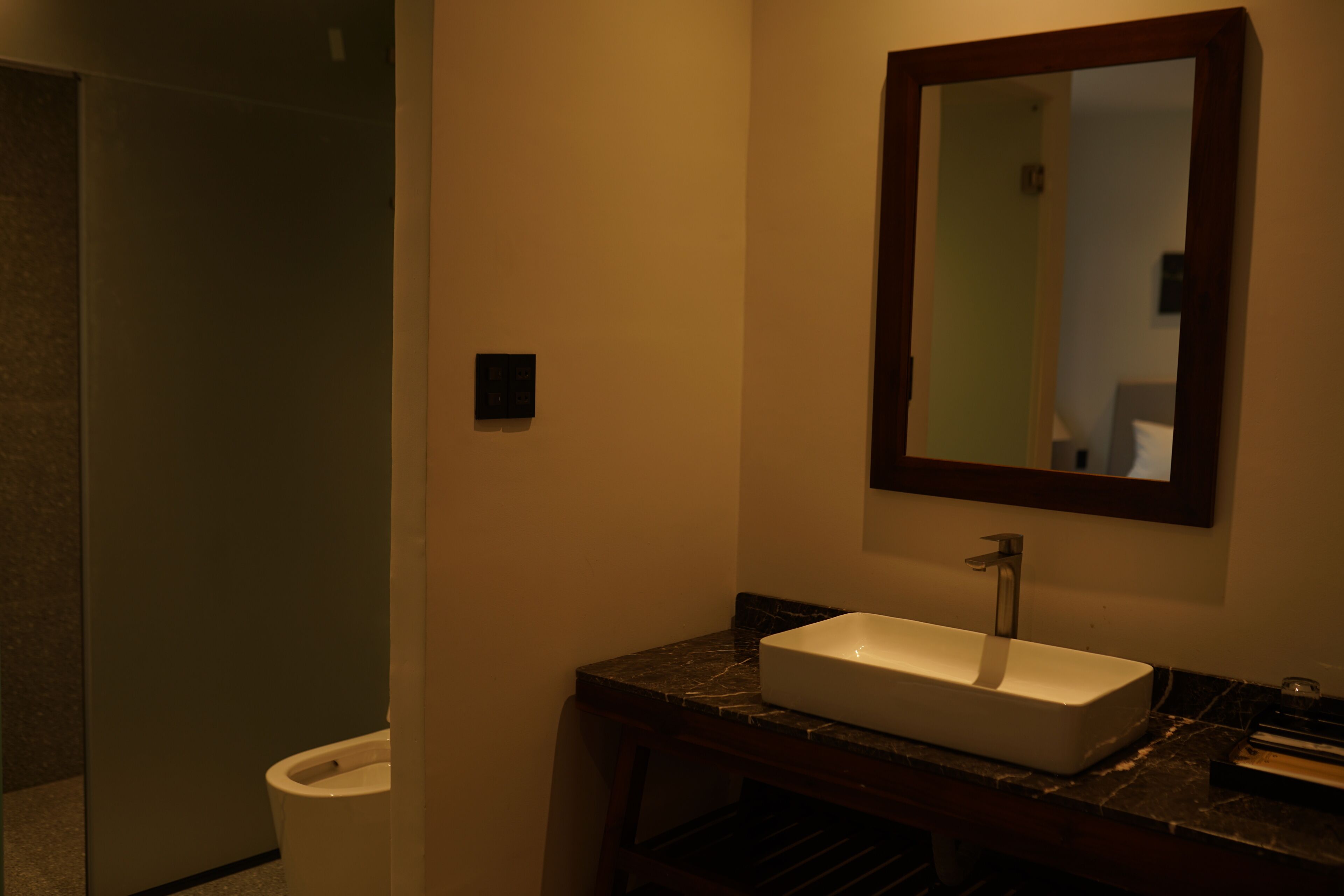 A bathroom with a white sink, dark marble countertop, and a mirror above the sink.