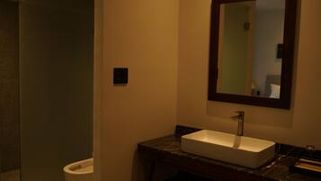 A bathroom with a white sink, dark marble countertop, and a mirror above the sink.
