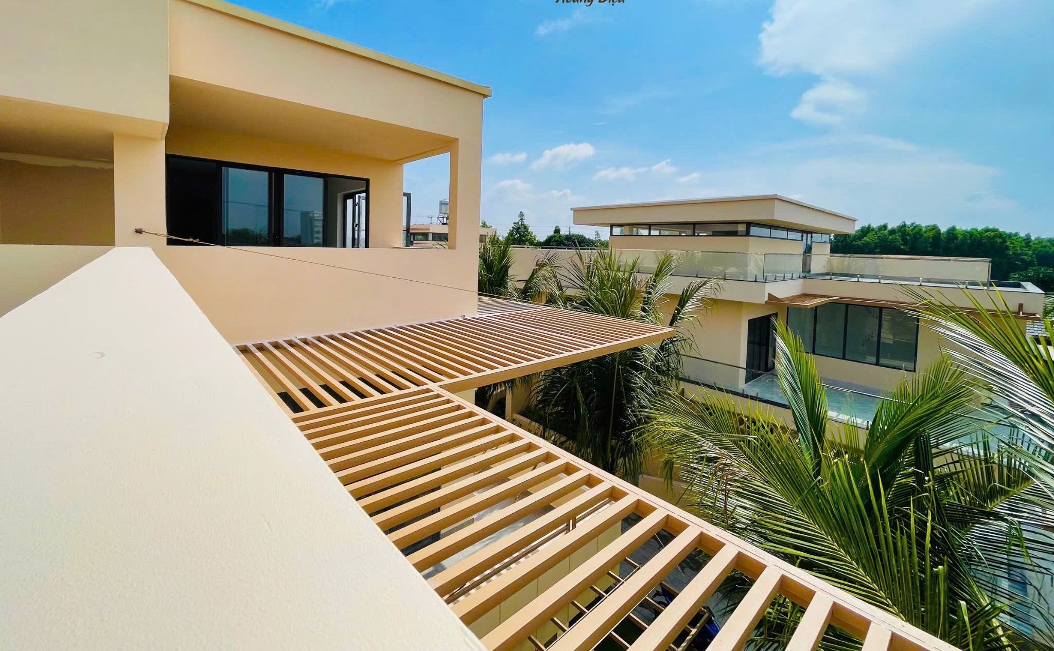 A modern villa with a flat roof, large windows, and a wooden pergola.