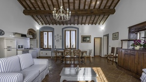 A spacious living room with a dining area, kitchen, and a wooden ceiling. - Noce Cottage With Pool, Casole D'elsa (Casole D'elsa)