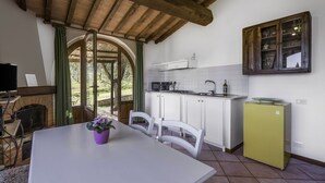 Uma cozinha com armários brancos, uma geladeira verde e uma janela com vista para um jardim.